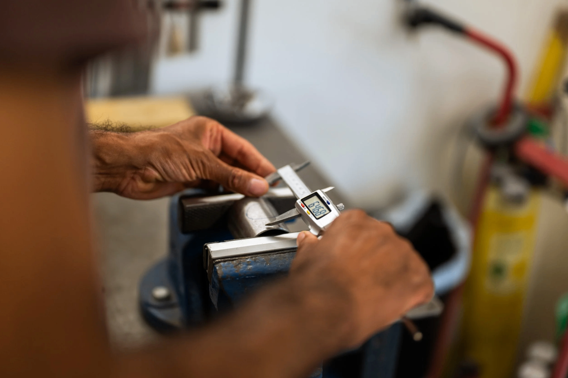 Hands measuring a tube with digital calipers