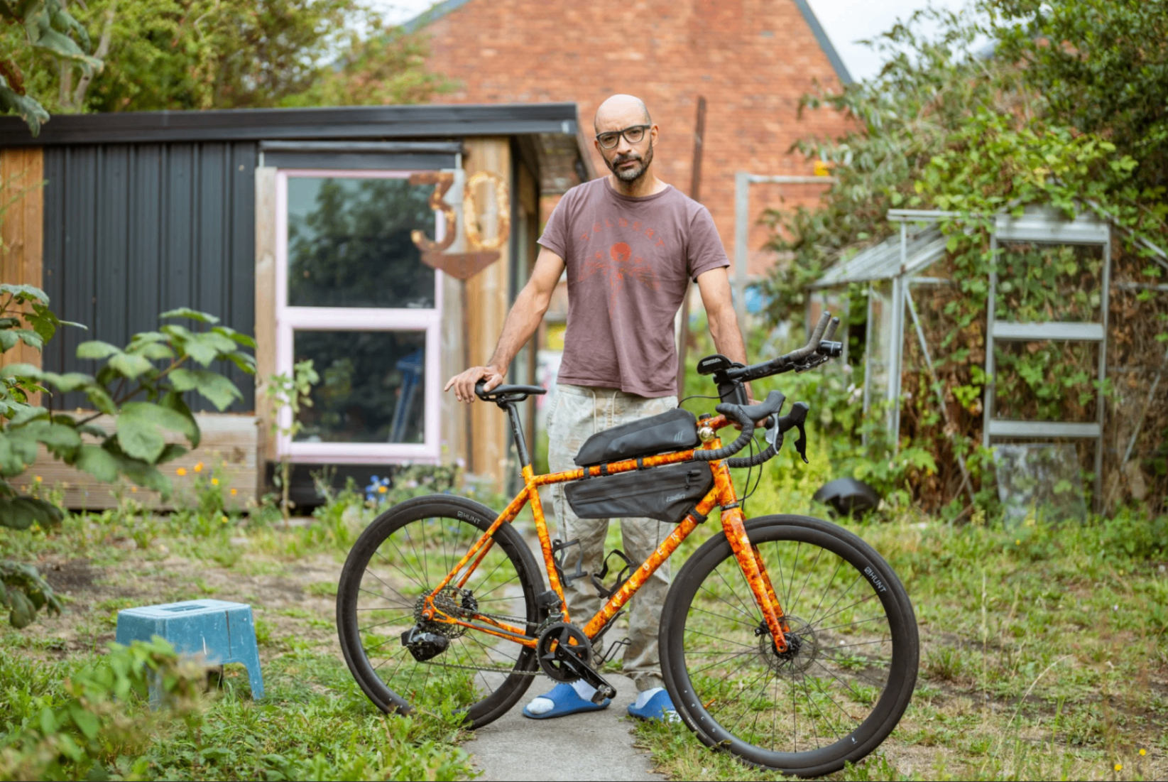 Telbert of Telbert Cycles with his orange gravel bike outside his workshop
