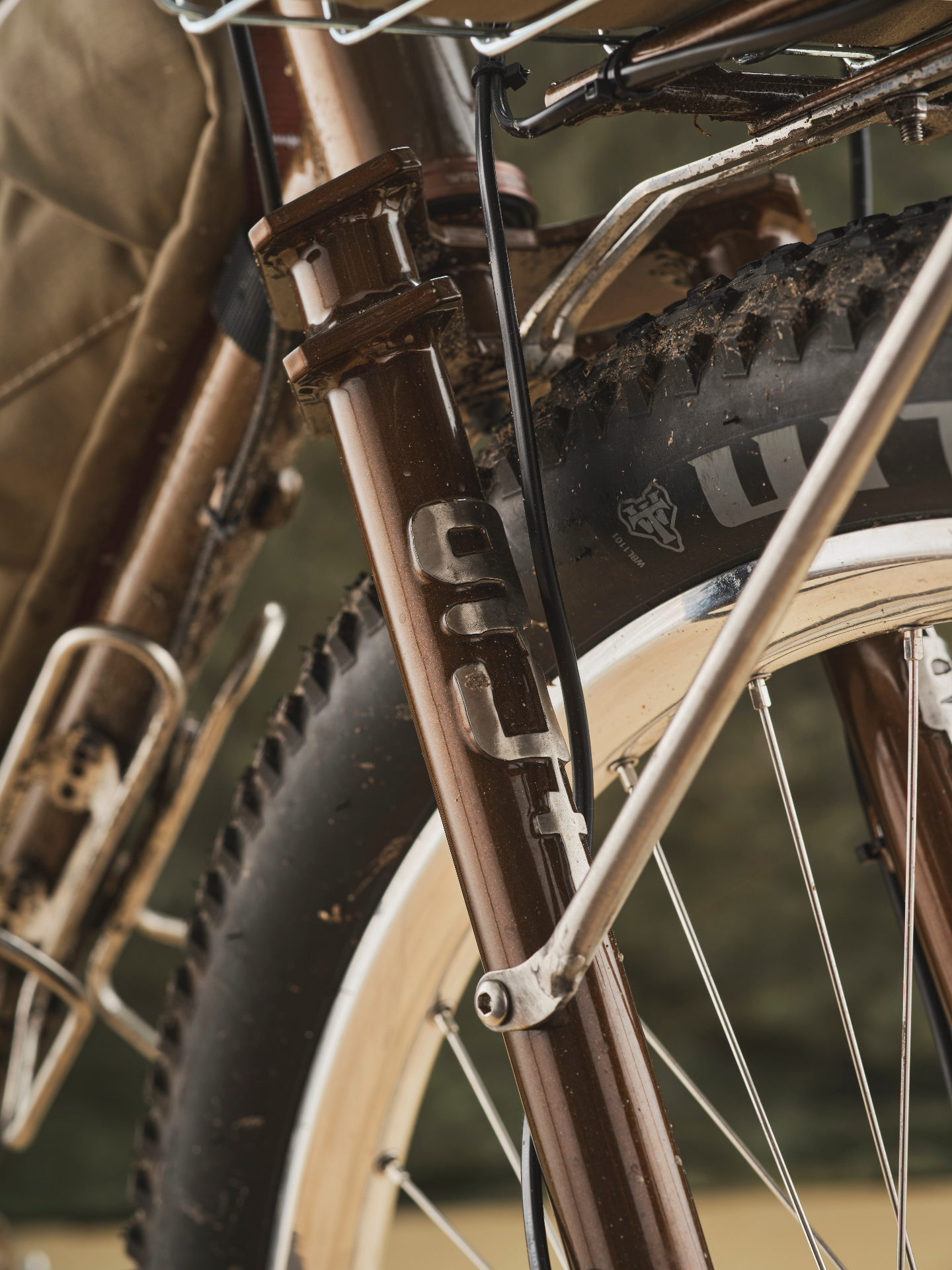 Close-up of a custom brown steel fork with WTB tyre, splattered with mud