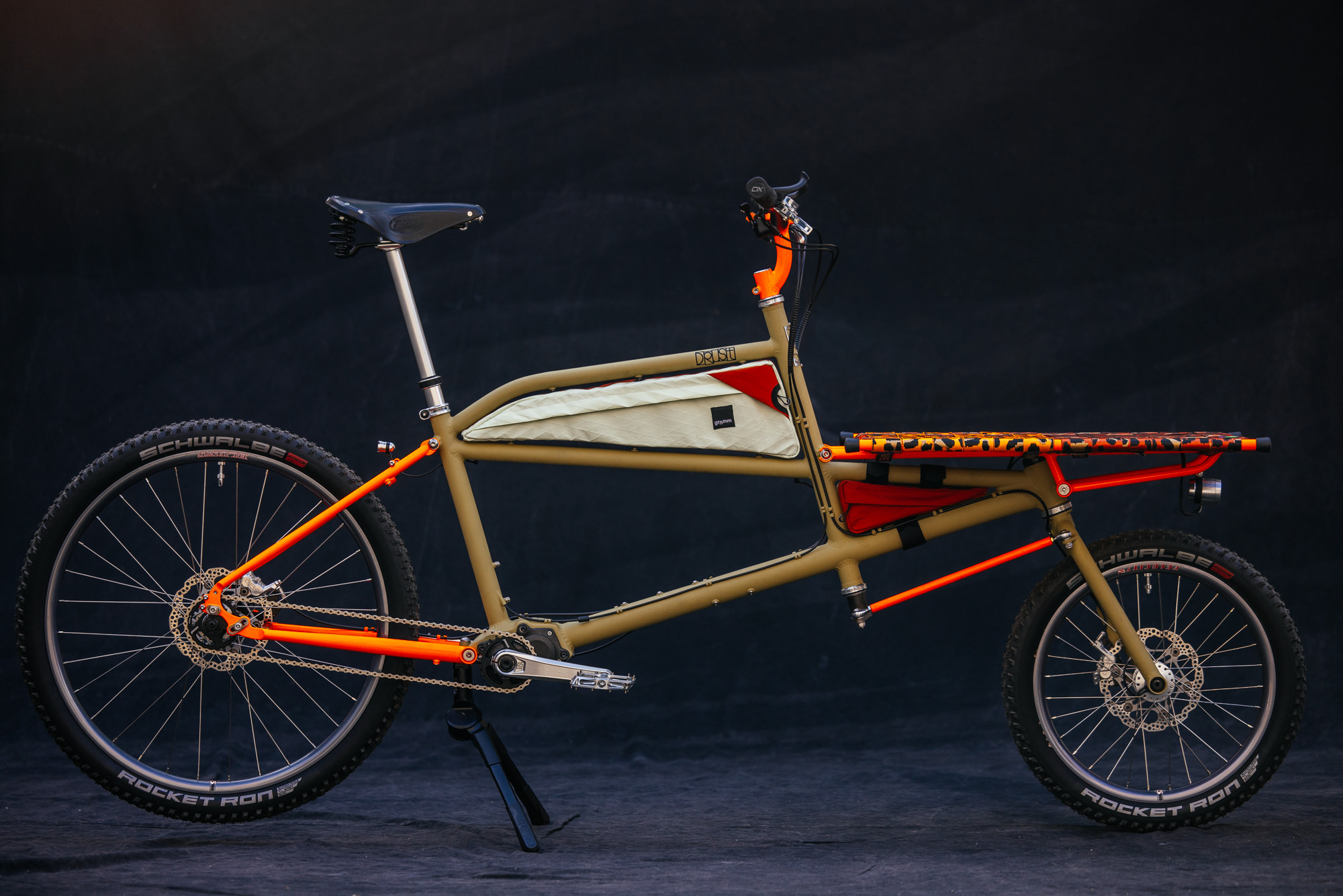 A Drust Klunkargo cargo bike in olive and orange with a Gramm frame bag