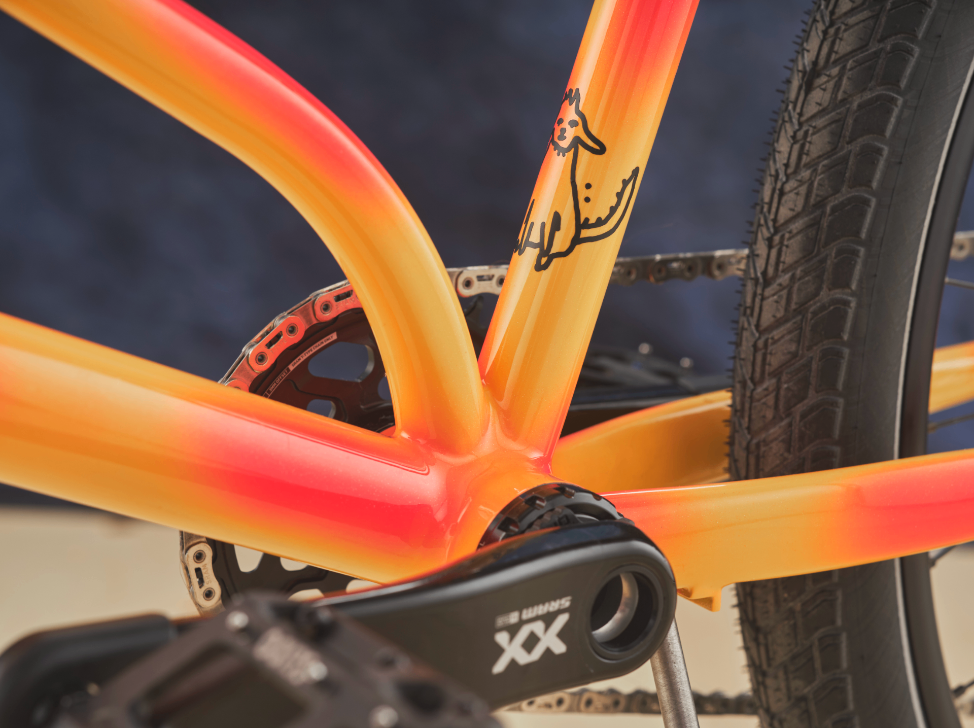Close-up of an orange custom frame with hand-drawn artwork and SRAM XX crank