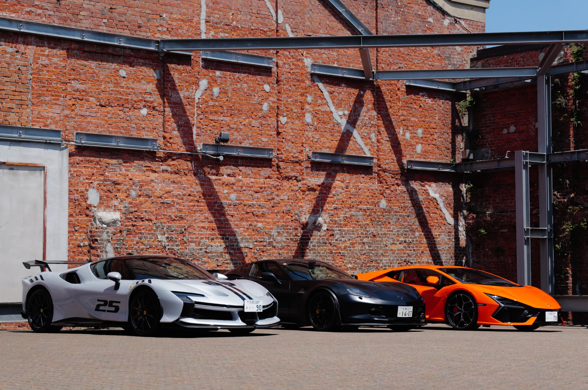 Three sports cars outside the red-brick GLION venue in Osaka