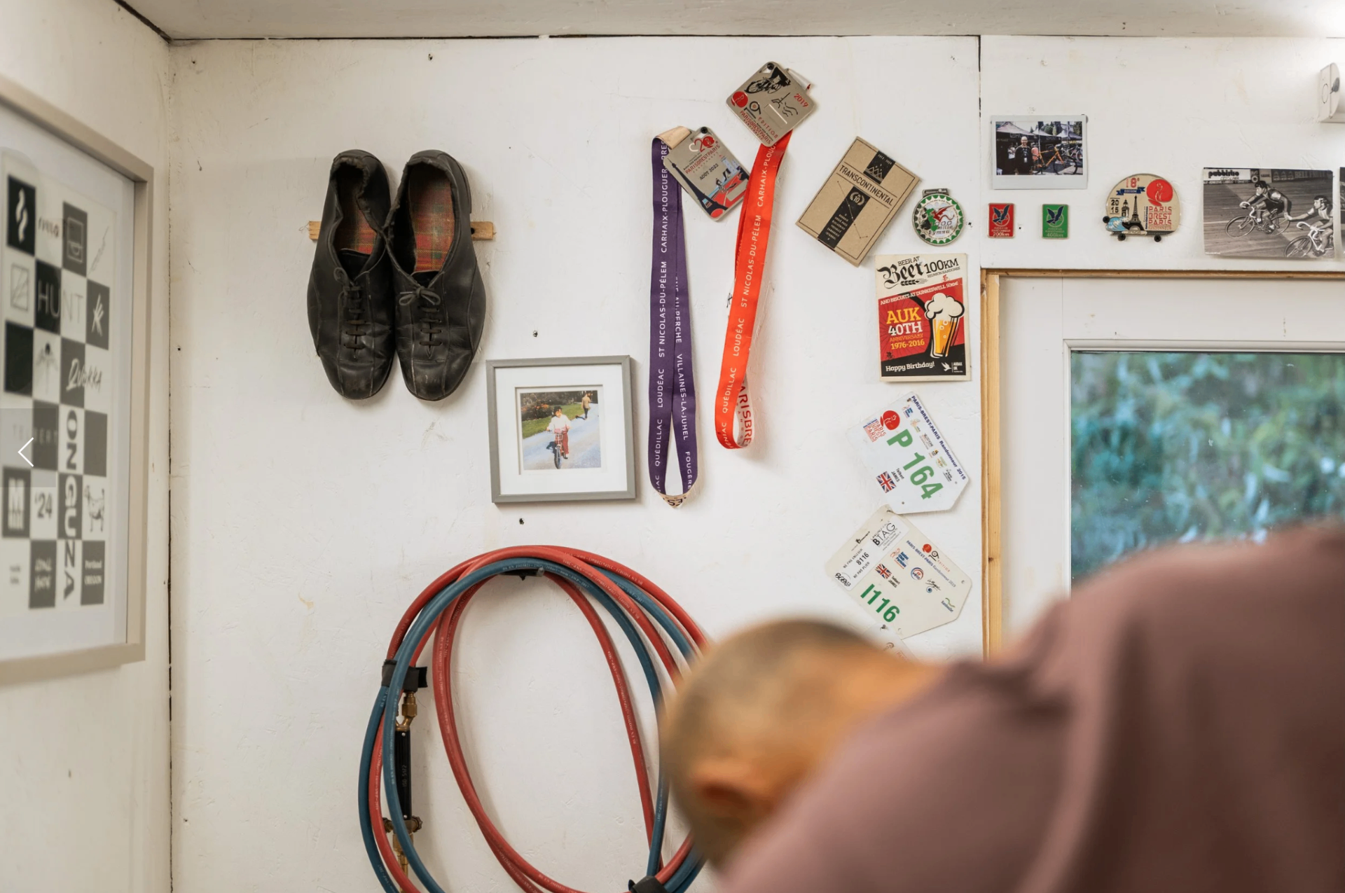 Workshop wall with old cycling shoes, Paris-Brest-Paris medals and race numbers