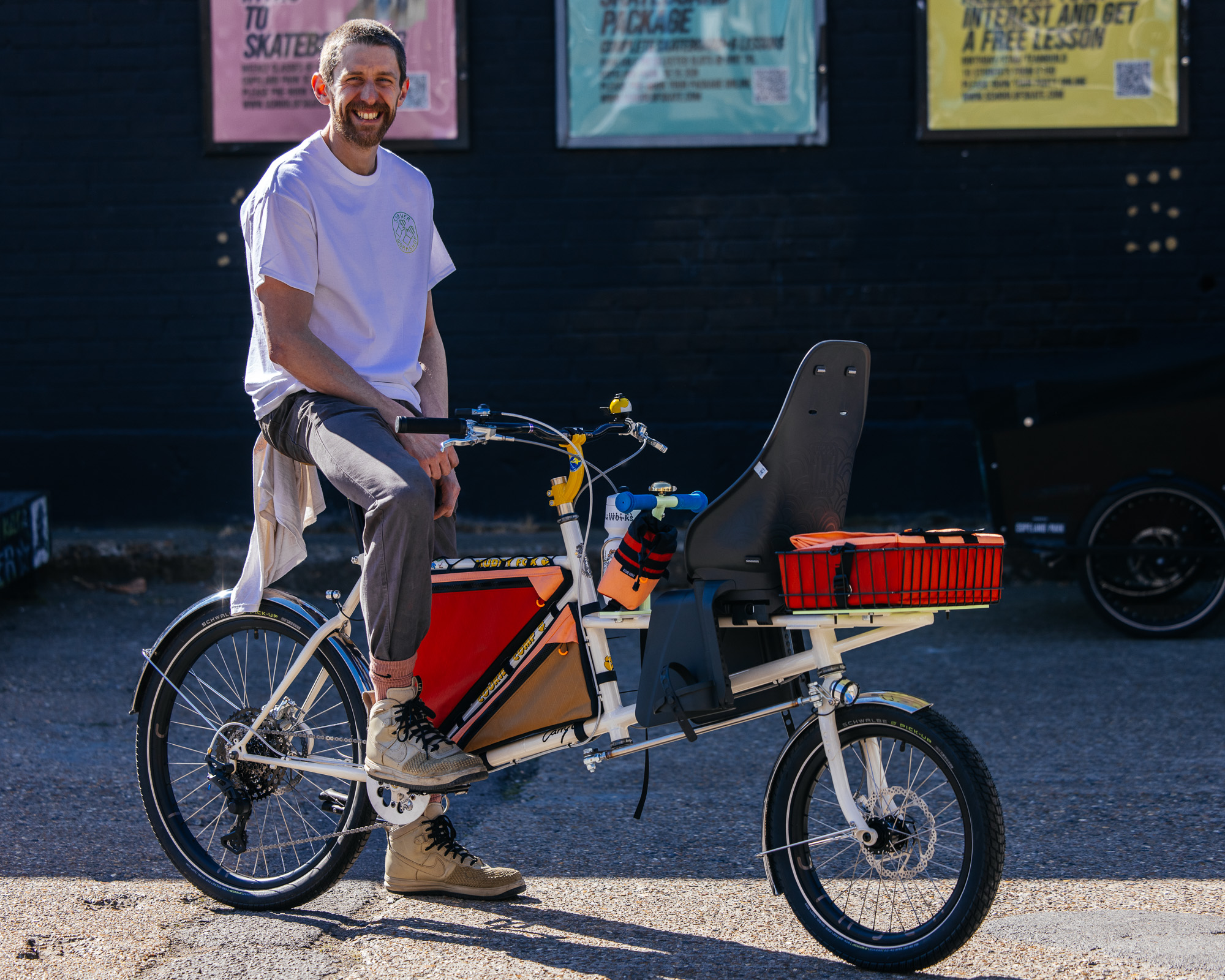 A framebuilder sitting on a white Muddy Fox cargo bike